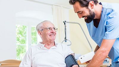 Nursing professional measures blood pressure of an elderly man